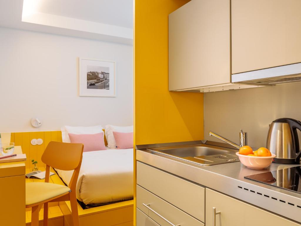 An open-plan studio showing the bed, compact desk and adjoining kitchenette.