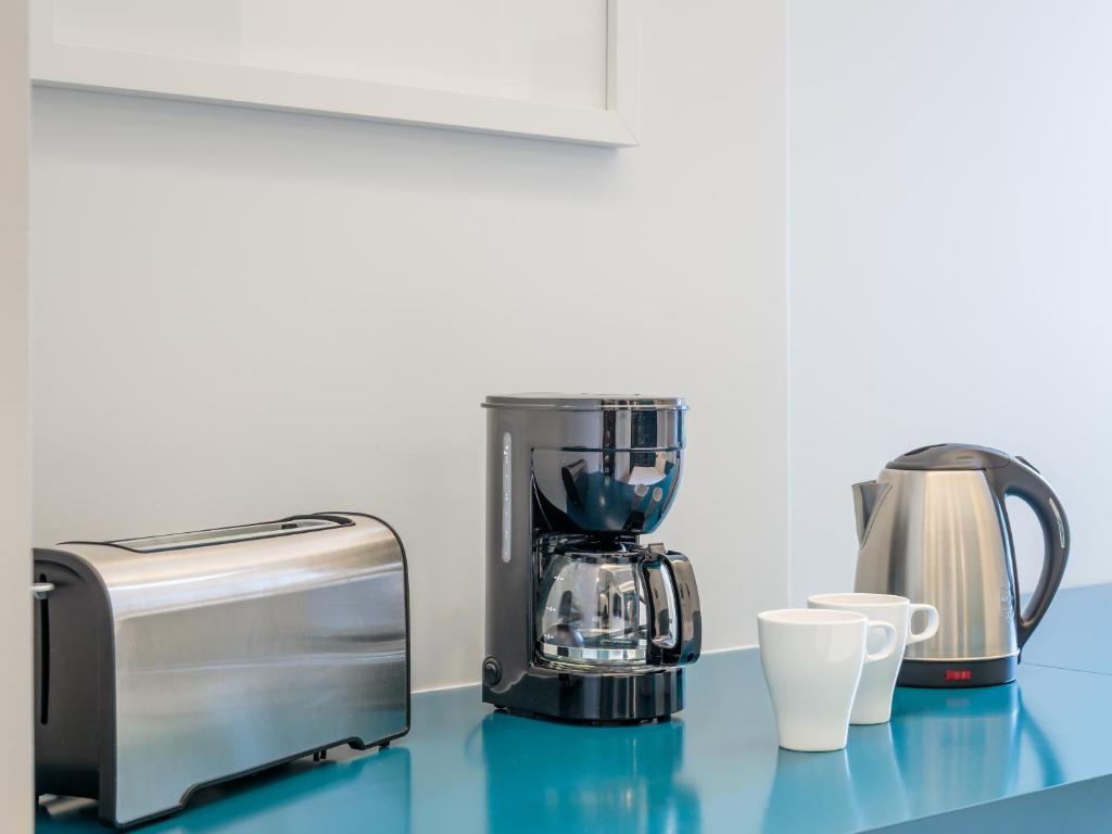 A kitchenette counter stocked with a toaster, drip coffee maker and electric kettle.