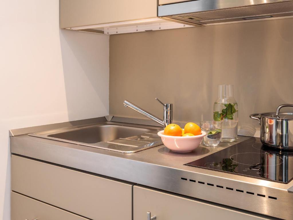 A compact kitchenette with a sink, induction hob and stainless-steel cooking area.