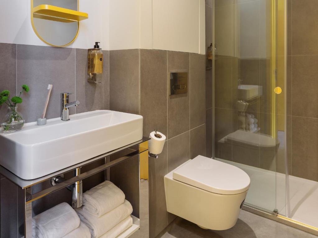 A modern bathroom with a wall-mounted toilet, vanity sink and enclosed shower.