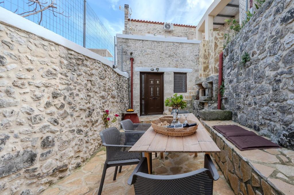 eine Terrasse mit einem Tisch, Stühlen und einer Steinmauer in der Unterkunft Kalimera Loft I , Village Experience in Argyroupoli