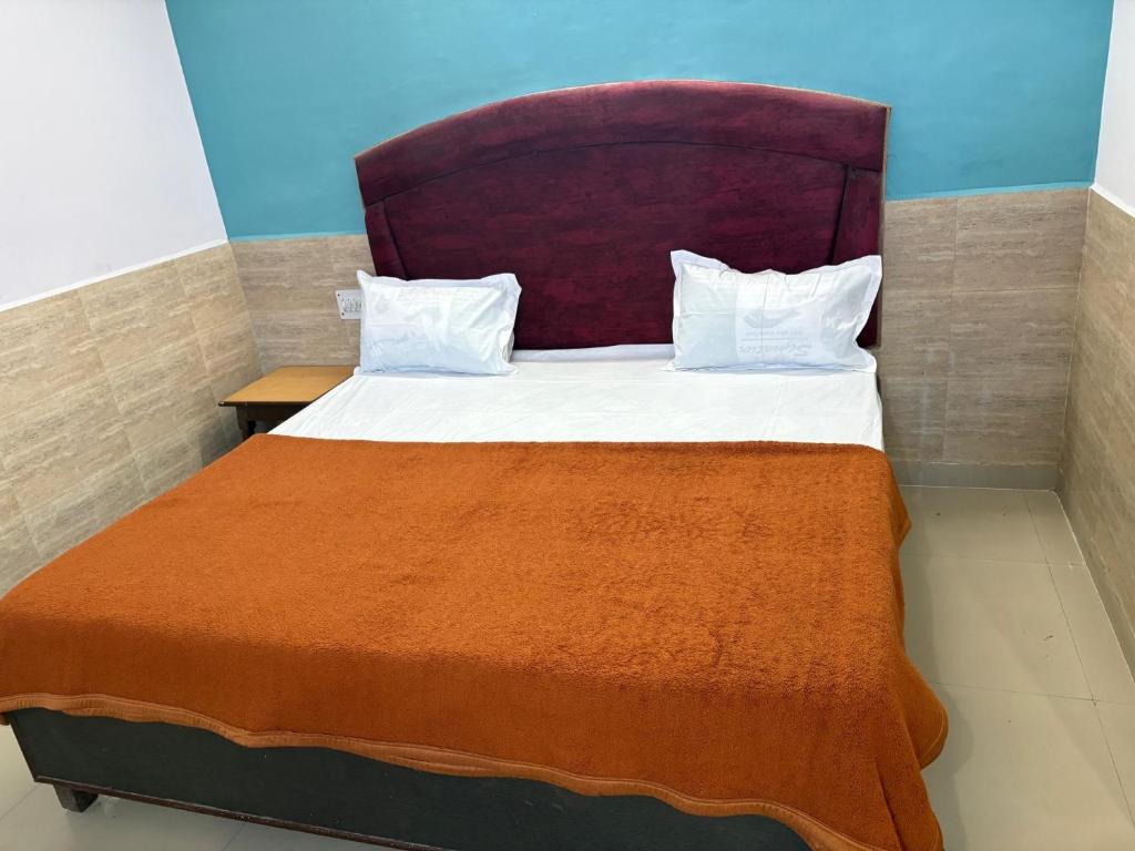 a bedroom with a large bed with a orange blanket at Hotel Mohan in Agra