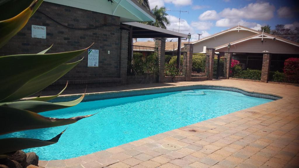 een zwembad in een tuin naast een huis bij Cattleman's Rest Motor Inn in Charters Towers
