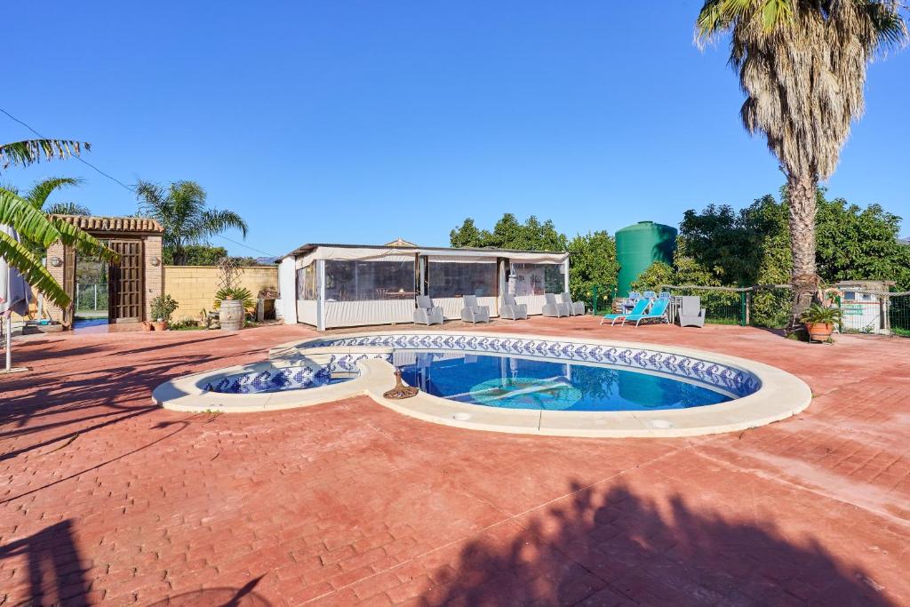 einen Pool im Garten mit Palmen in der Unterkunft Cortijo Palomo in Benamocarra