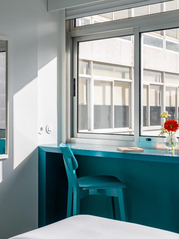A compact turquoise desk and chair set beside a bright window.