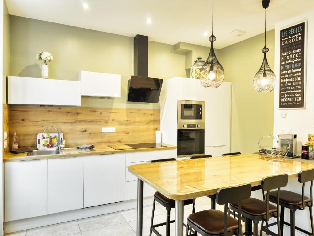 a kitchen with white cabinets and a wooden table at Au Beau Duplex de la Basilique in Boulogne-sur-Mer