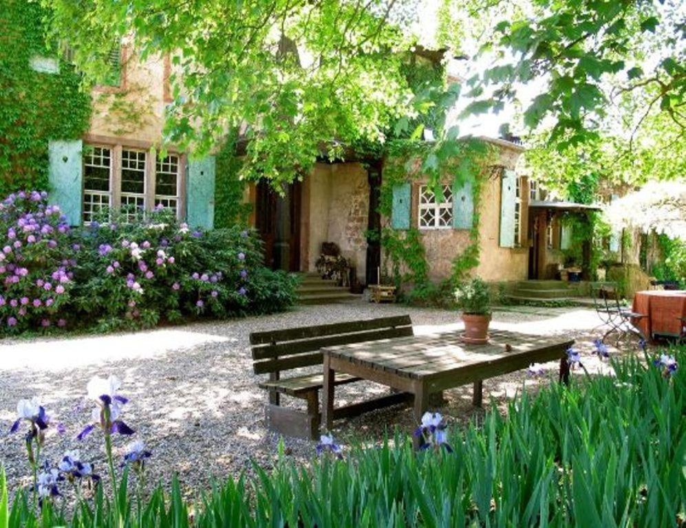 a picnic table in front of a house with flowers at Chambres d'hôtes Le Clos Saint Léonard in Boersch