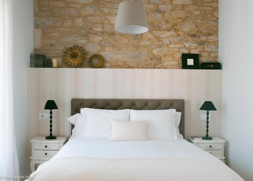 a bedroom with a bed with a stone wall at A galería do san Ramón in Villalba