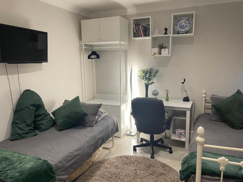 een woonkamer met een bank en een bureau met een stoel bij Costa del Pinner in Northwood