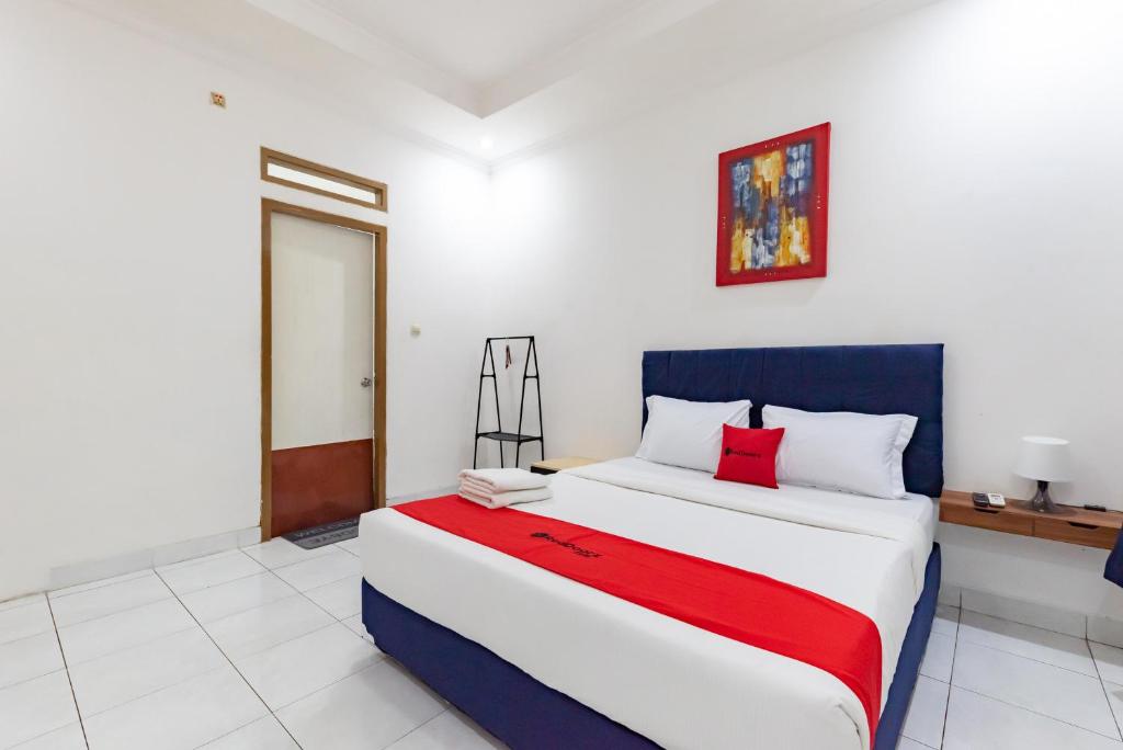 een slaapkamer met een groot wit bed met rode kussens bij RedDoorz Plus near Universitas Maranatha Bandung 2 in Bandung