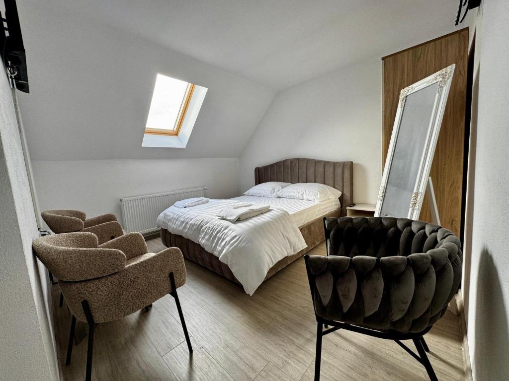 ein Schlafzimmer mit einem Bett, einem Spiegel und einem Stuhl in der Unterkunft Tudors Rooms in Mediaş