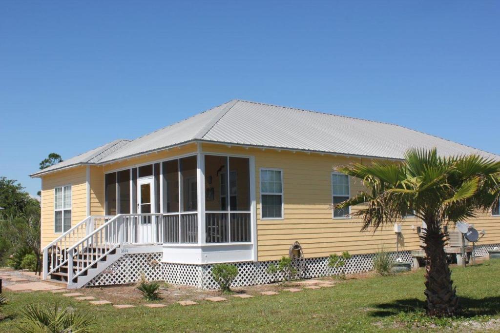 a yellow house with a porch and a palm tree at The Rookery Unit 3501 in Gulf Shores