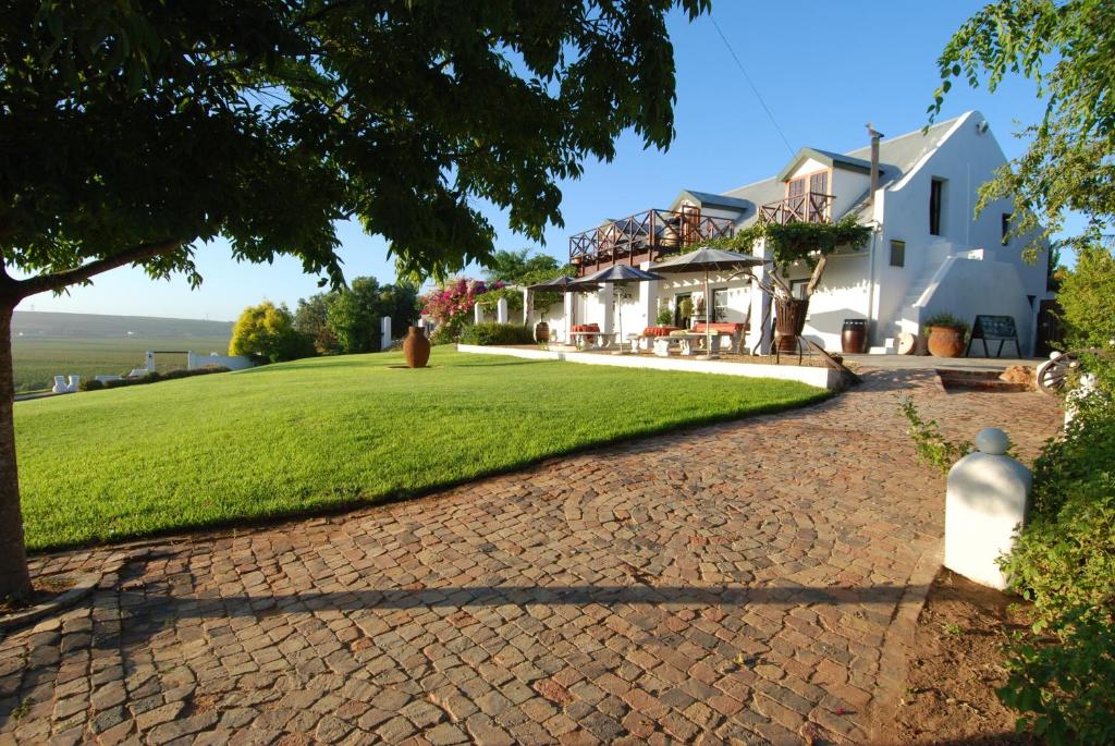 a cobblestone driveway leading to a house at Melkboomsdrift Guest House & Conference Centre in Vredendal