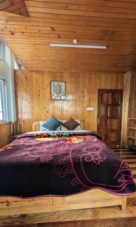 a large bed in a room with wooden walls at Foggy Hill's Darjeeling in Darjeeling
