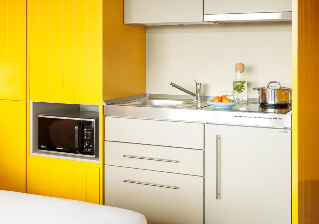 A compact kitchenette with a sink, cooktop, microwave, and under-counter refrigerator.