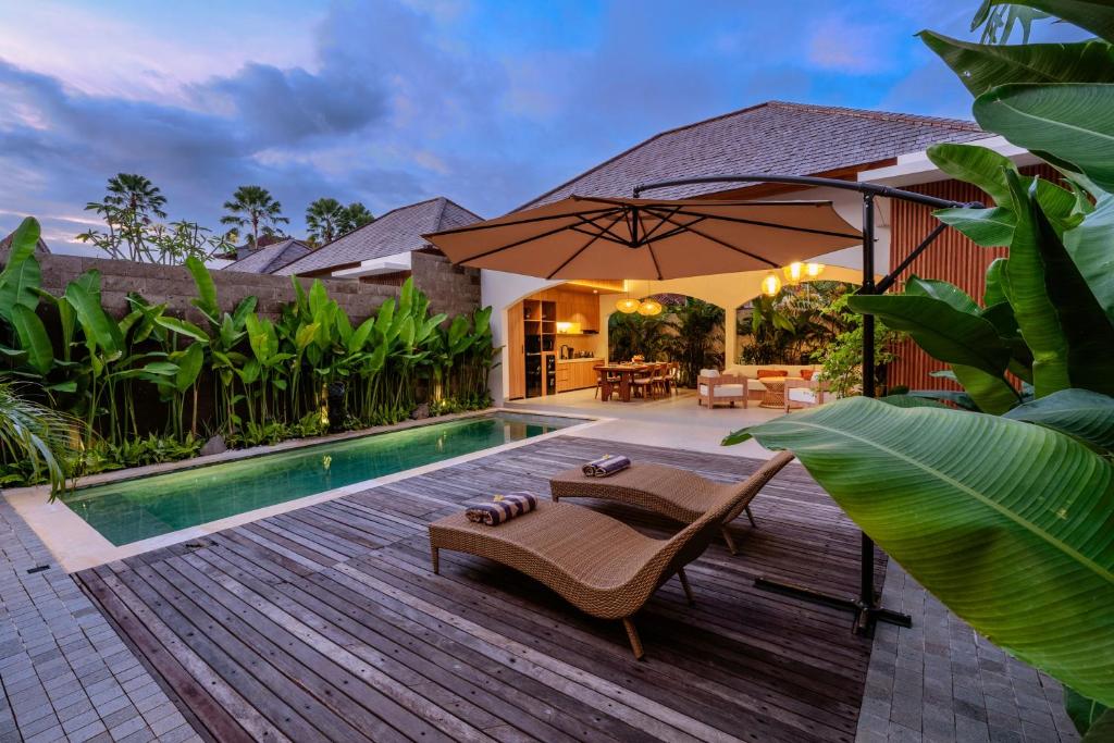 a backyard with a swimming pool and an umbrella at NAVA Ubud Villas in Ubud