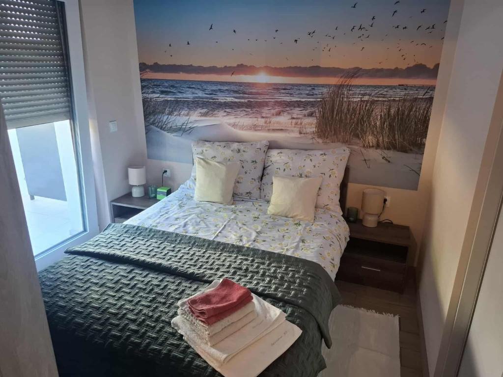een slaapkamer met een bed met een foto van een strand bij apartament MT2 bursztynowe osiedle in Jantar
