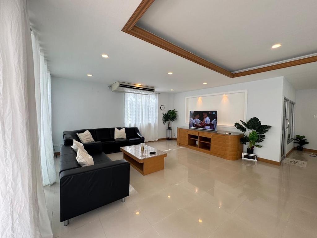 a living room with a black couch and a tv at Cozy Stay in Ban Nong Waeng
