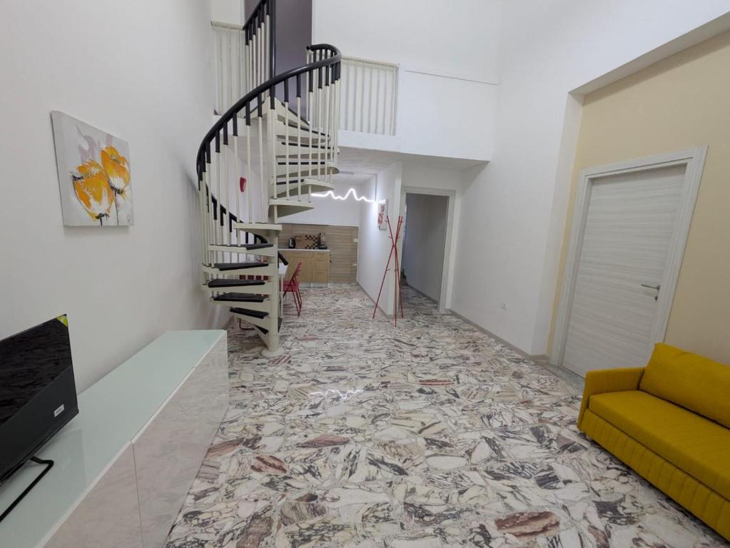 a living room with a staircase and a yellow couch at Domus Battisti in Caserta