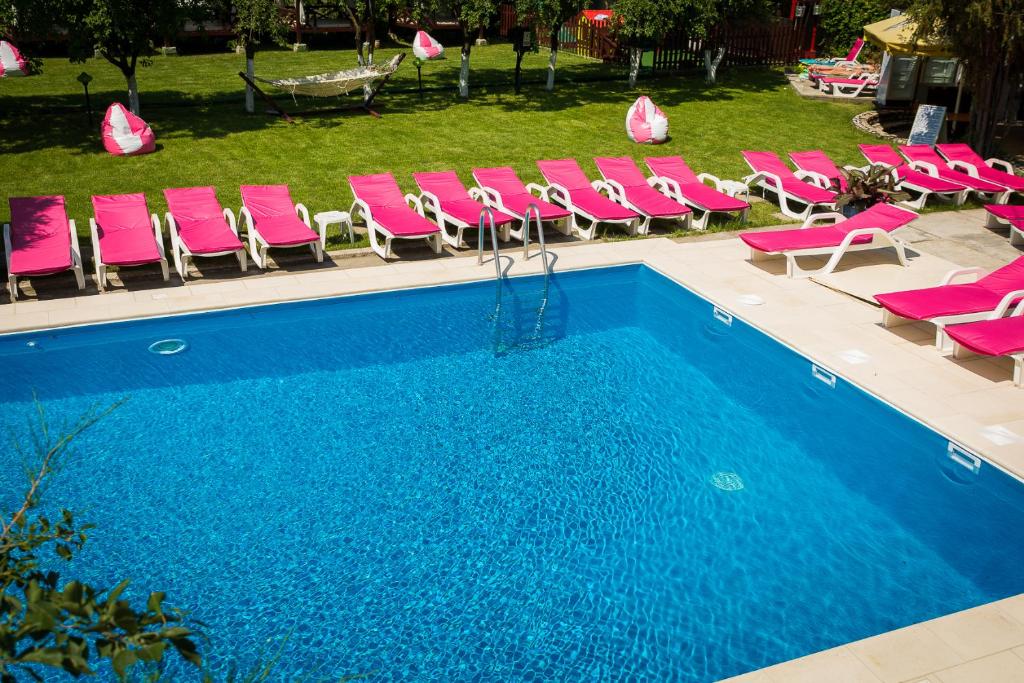a swimming pool with pink chairs and a bunch at Caprice Monteoru in Sărata-Monteoru