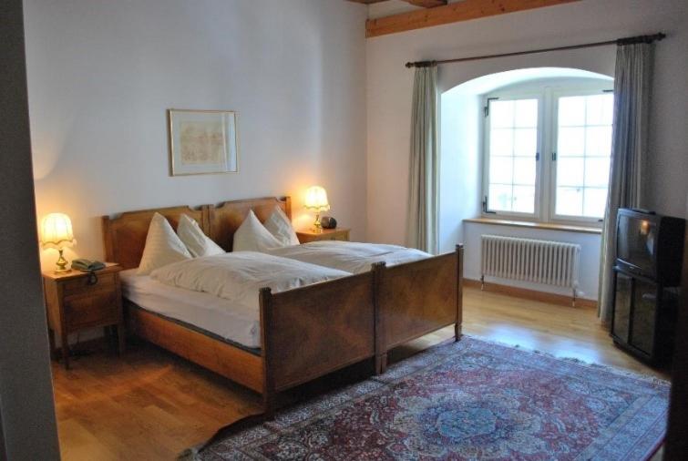 a bedroom with a large bed and a television at NRAR Hotel Hirschen in Beromünster