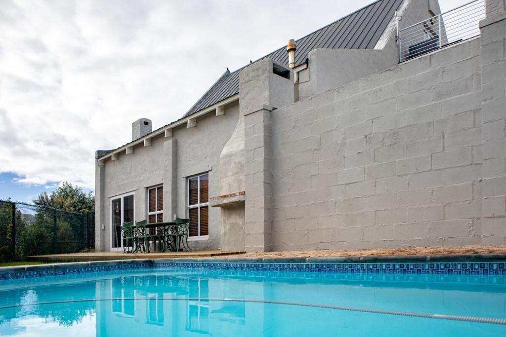 a house with a swimming pool in front of a building at Joan's Sea Cottage in Pringle Bay
