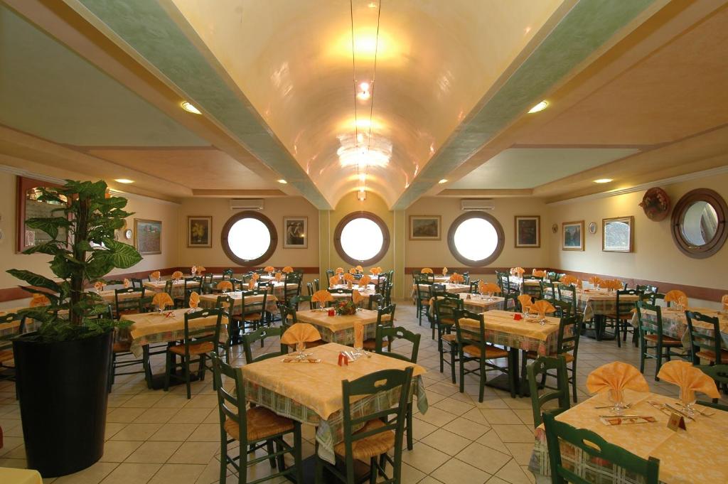 un comedor con mesas, sillas y ventanas en Hotel Ristorante Il Pirata en San Vito di Leguzzano