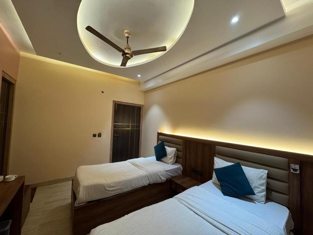 2 Betten in einem Zimmer mit Deckenventilator in der Unterkunft Jaiswal Dharmshala in Sultānpur
