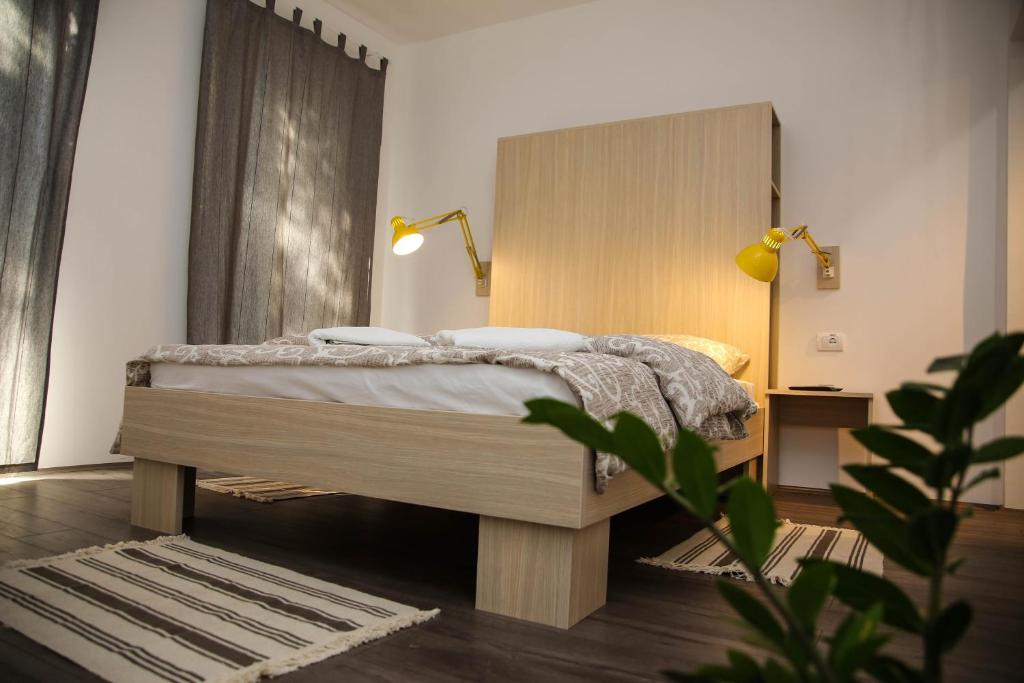 een slaapkamer met een bed met een houten hoofdeinde bij Apartmani Stan Na Dan in Šabac