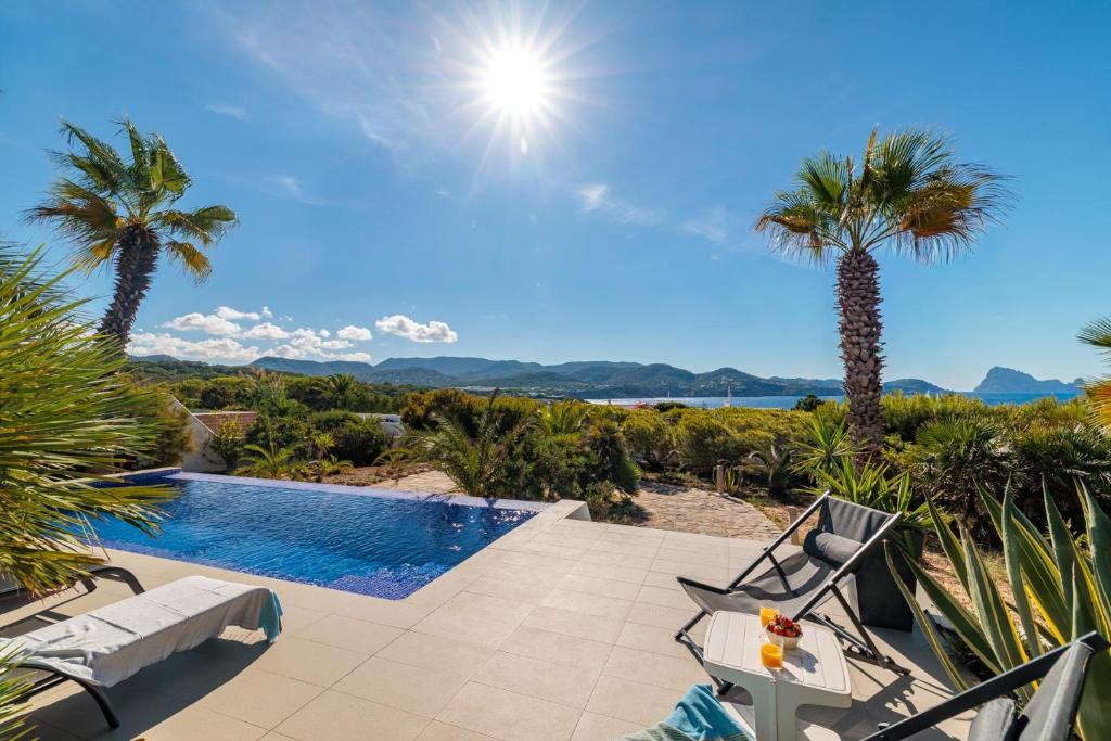 a villa with a swimming pool and palm trees at Casa Arola in Sant Josep de sa Talaia