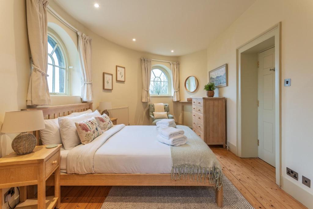 een slaapkamer met een bed met witte lakens en 2 ramen bij Bath Lodge in Tormarton