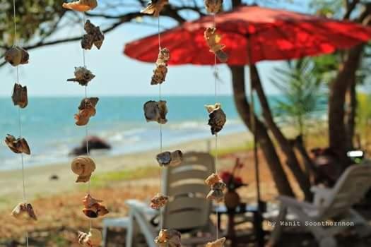 a beach with chairs and a red umbrella and some shells at Dugong Koh Sukorn in Ko Sukon