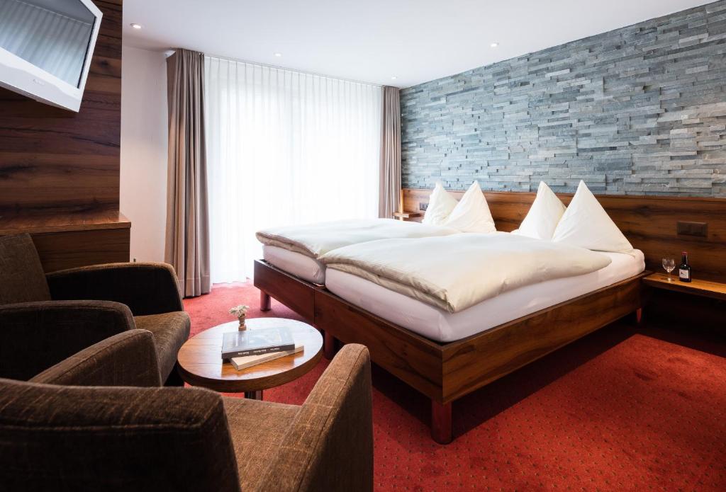 una camera con letto e un soggiorno con sedie di Hotel Continental a Zermatt
