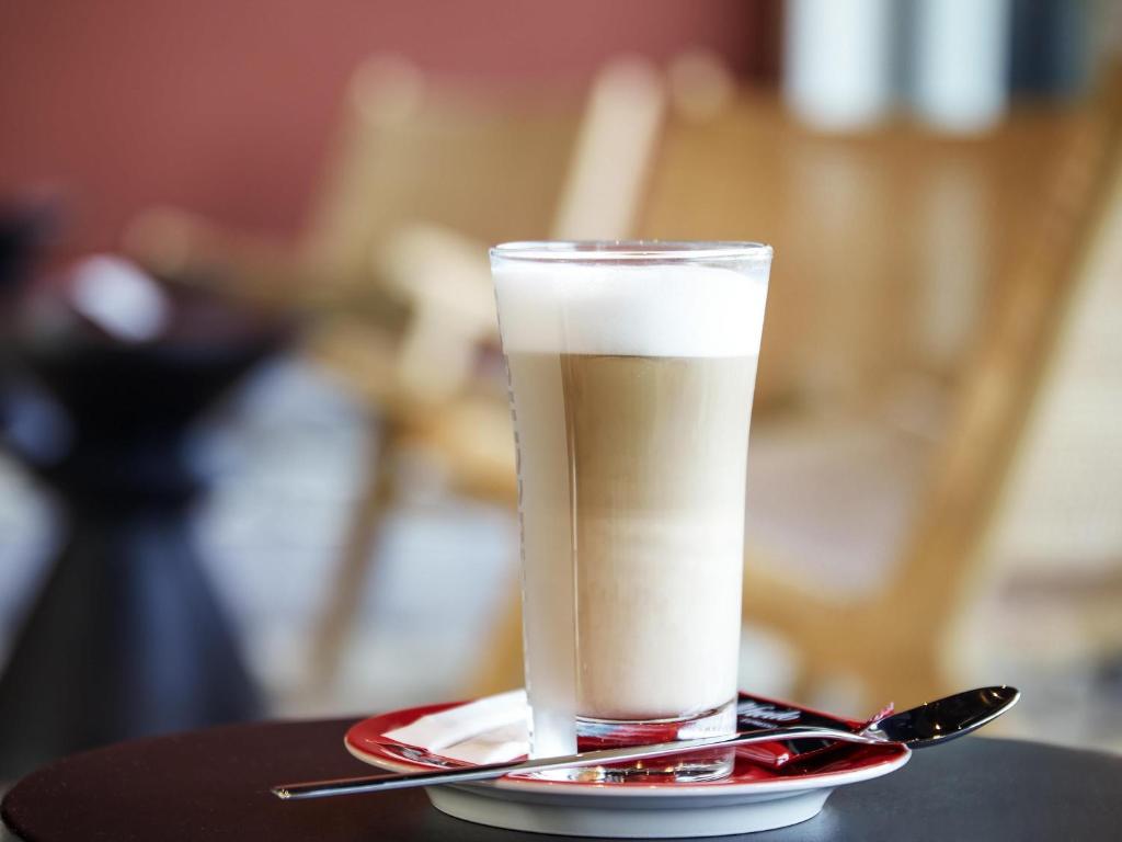 a glass of milk on a plate with a spoon at ibis budget Bayreuth in Bayreuth
