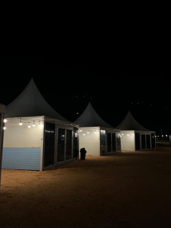 eine Reihe weißer Zelte mit Lichtern in der Dunkelheit in der Unterkunft خيم مبيت ملكية بالصياهد in Rumāḩ