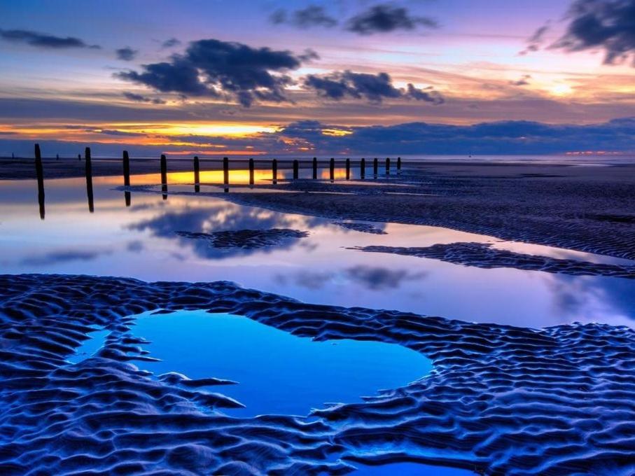a reflection of a pier in the water at sunset at Las Palmas Hotel by the Sea in Blackpool