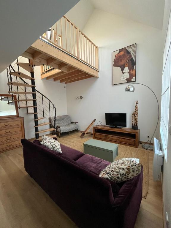 a living room with a couch and a staircase at La maison de l'orée de la forêt in Hasnon
