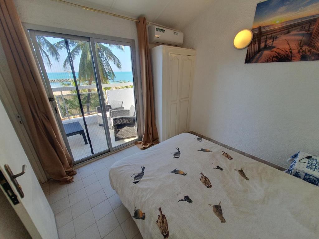 a bedroom with a bed with a view of the ocean at Villa de la Plage sous les cocotiers in Saly Portudal