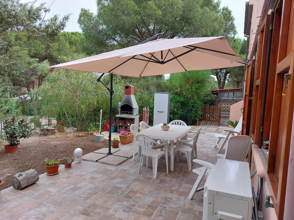 een patio met een parasol en een tafel en stoelen bij Cattari House in Marina di Sorso