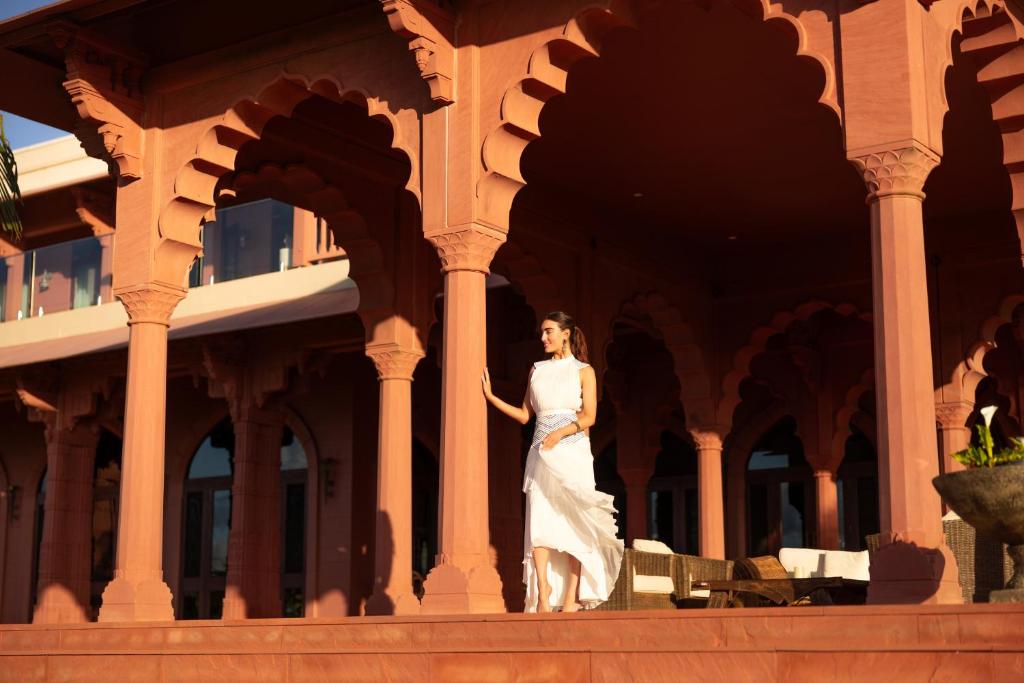 Eine Frau in einem weißen Kleid, die vor einem Gebäude steht. in der Unterkunft Jodha Bai Retreat in Terranora