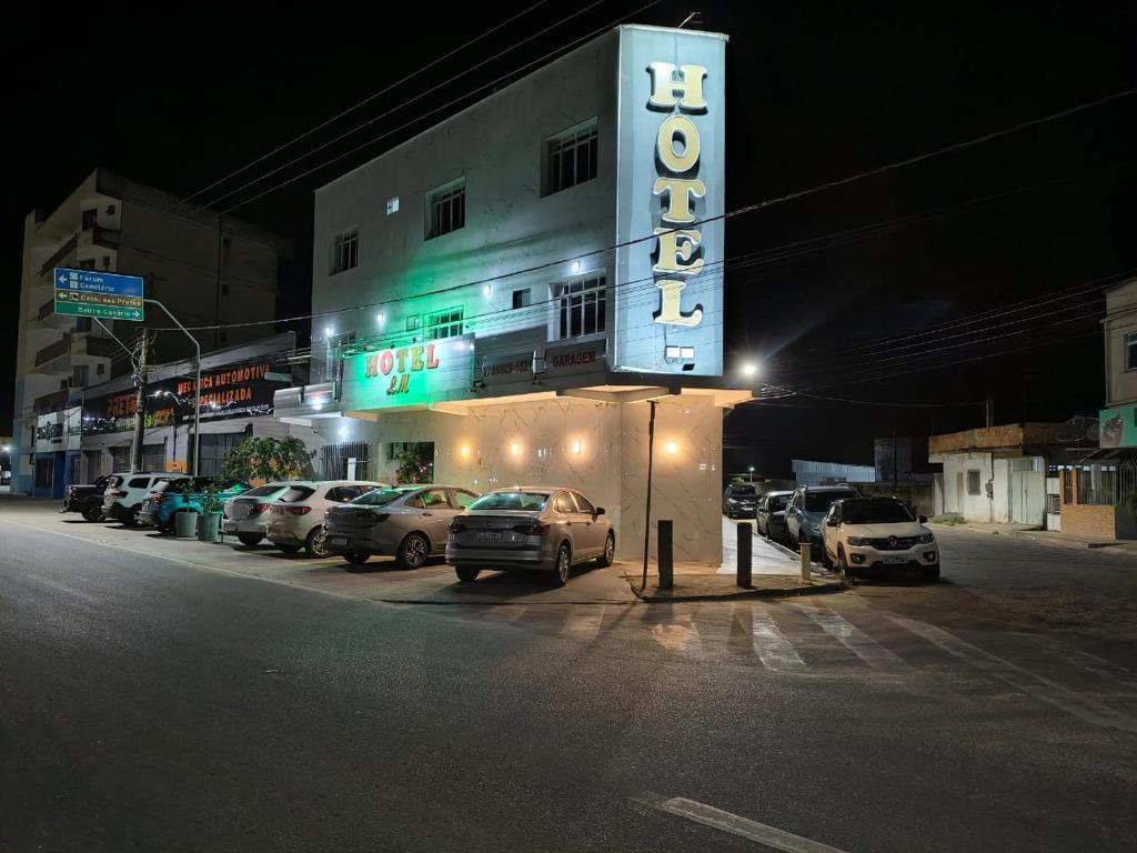 a hotel sign with cars parked in a parking lot at Hotel Lm in Pedro Canário