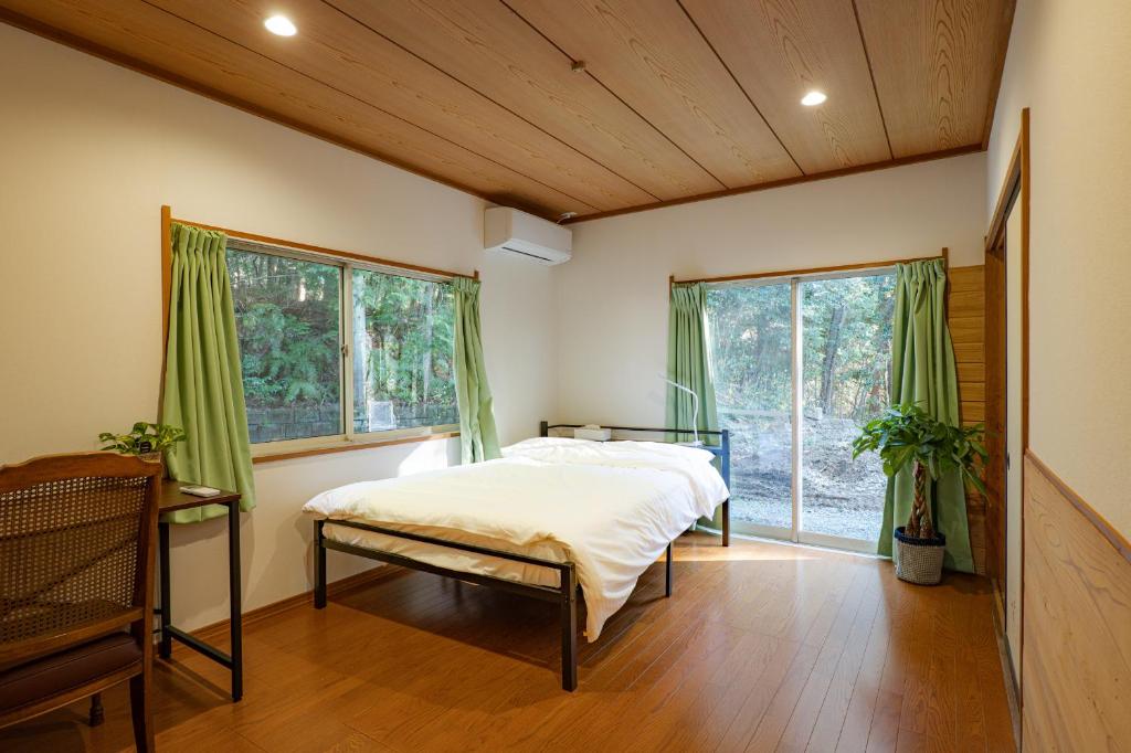 a bedroom with a bed in a room with windows at Lake&Mountain Hamamatsu inn in Hamamatsu
