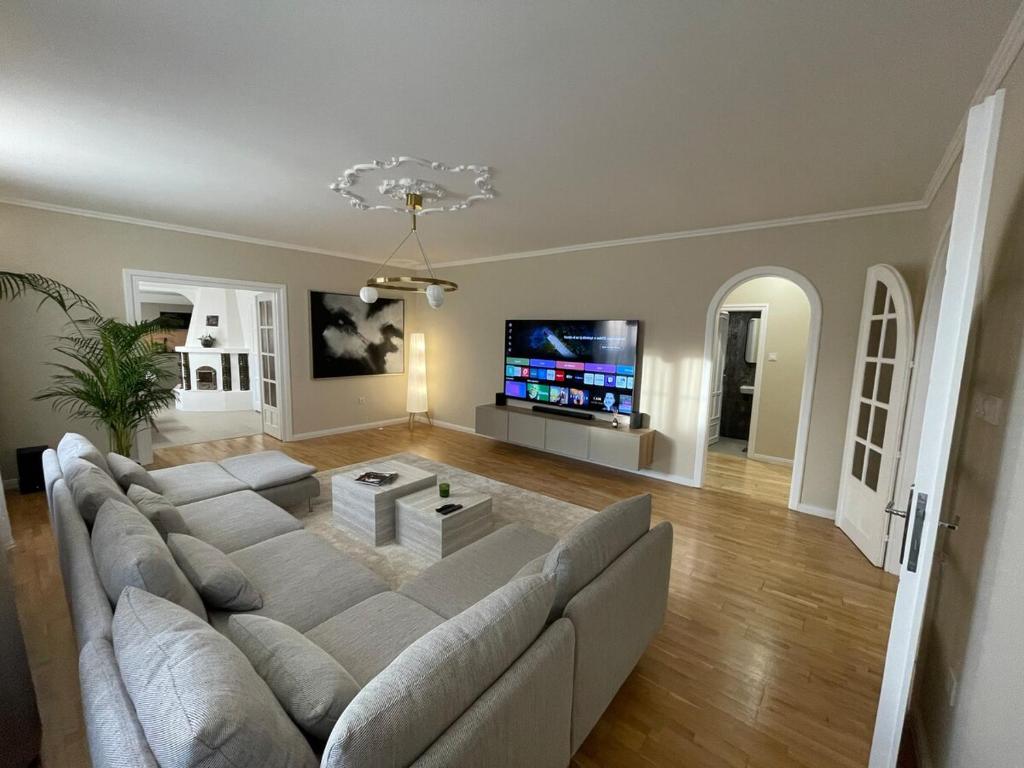 a living room with a large couch and a flat screen tv at Sóstó Liget House in Igricetanya