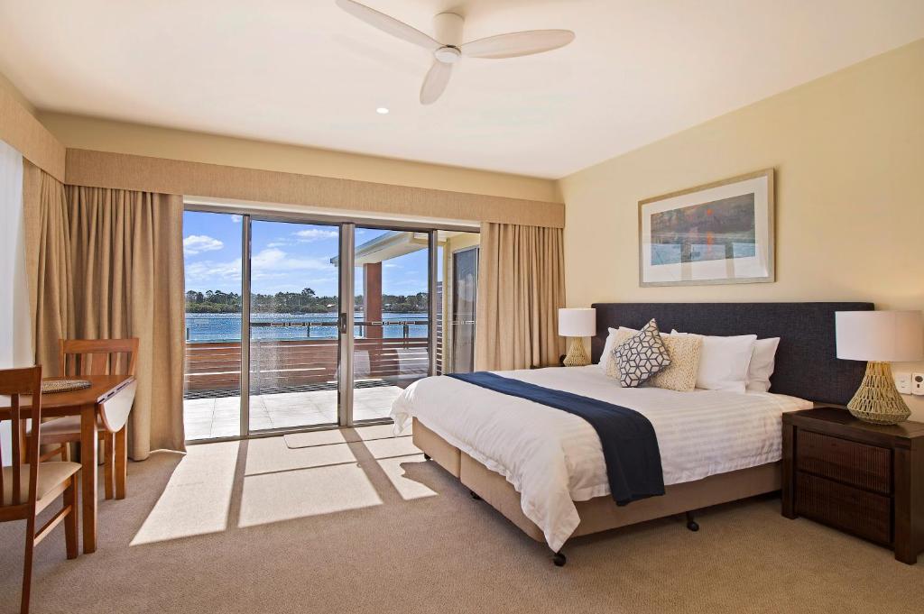 1 dormitorio con cama, escritorio y balcón en Ana Mandara Luxury Retreat, en Port Macquarie