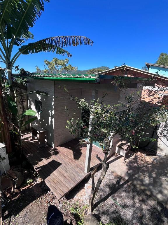 a wooden deck next to a house with a tree at Tiny House Armação no Morro in Florianópolis
