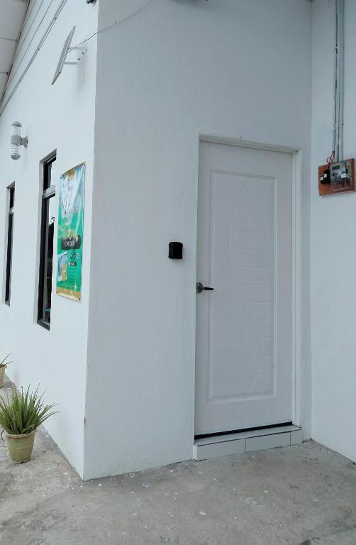 a white door in a white wall with a plant at Homestay Rezquna Deluxe Studio in Beaufort