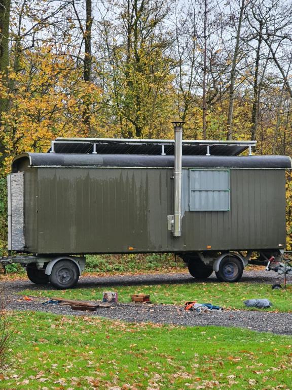 a green train car sitting on the tracks at De Schamelwagen in Bant