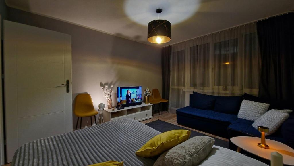 een slaapkamer met een blauw bed en een bank bij Apartament Granatowy Chill in Łódź