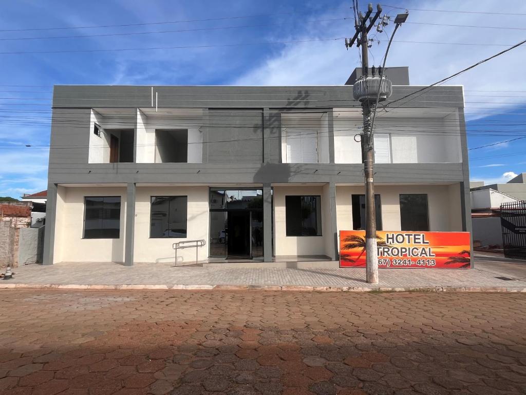 ein weißes Gebäude mit einem Schild davor in der Unterkunft Hotel Tropical in Aquidauana