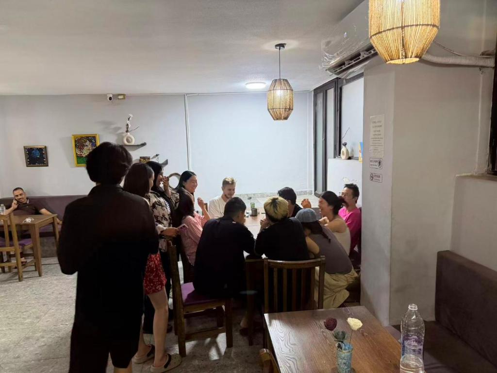 a group of people sitting around a table in a room at Galaxy Hostel华人青年旅舍 in Alexandria